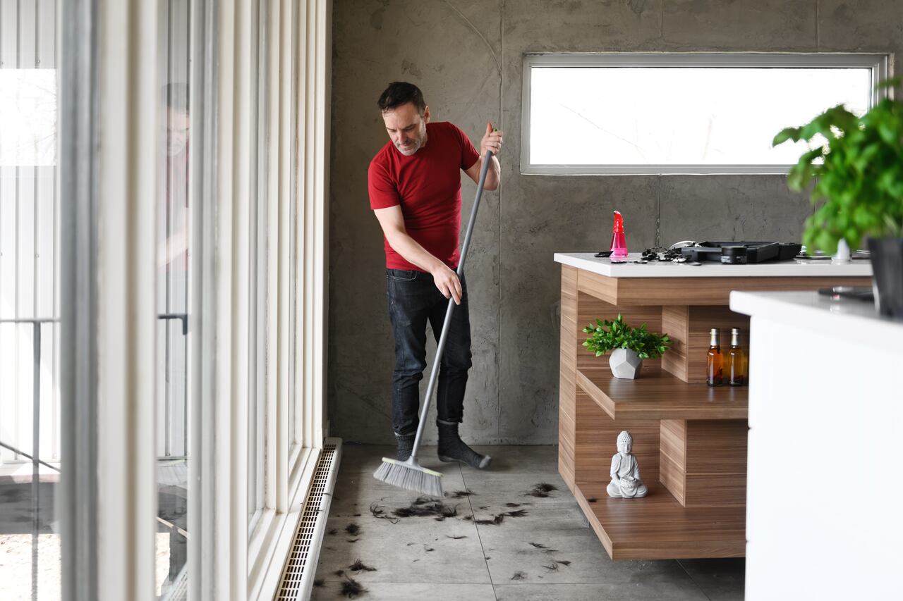 Man sweeping the floor after an homemade hairdcut, Quebec, canada